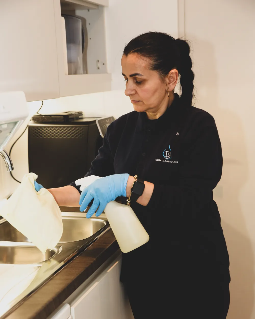 Une agente Bora Clean nettoie le plan de travail d'une cuisine de bureau en journée