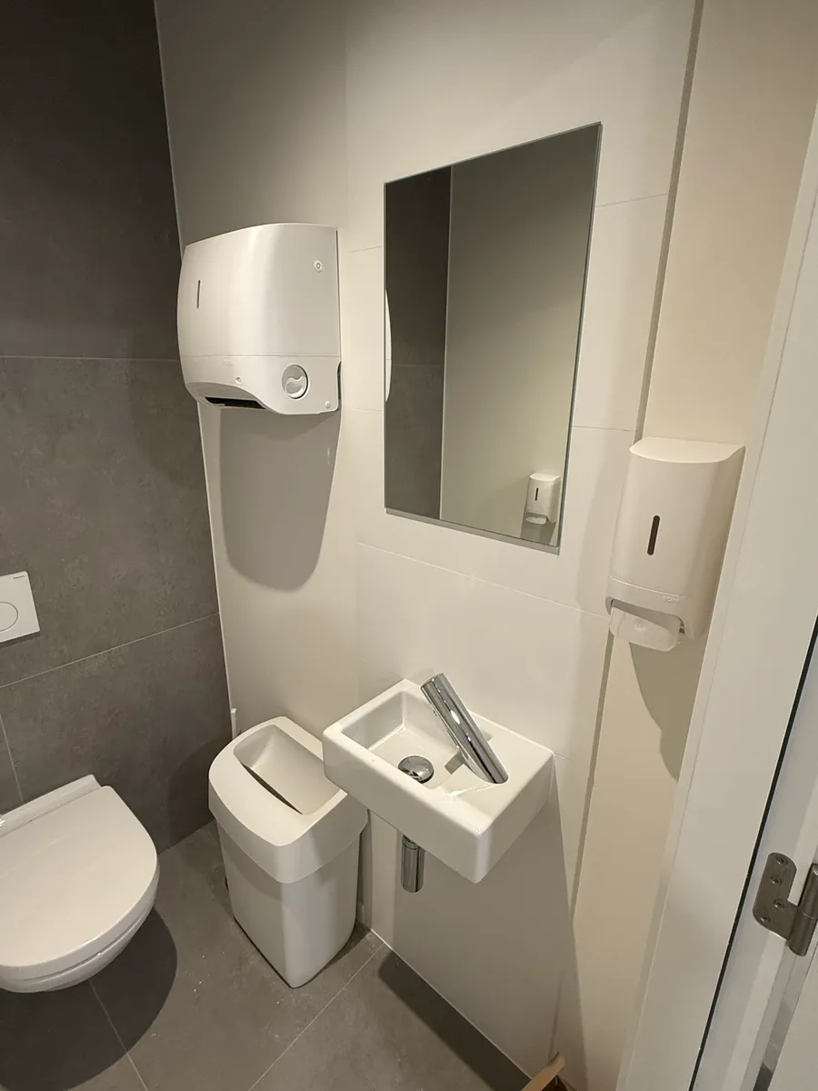 Sanitaires de bureau propres : lave-mains, miroir, distributeurs de savon et d'essuie-mains