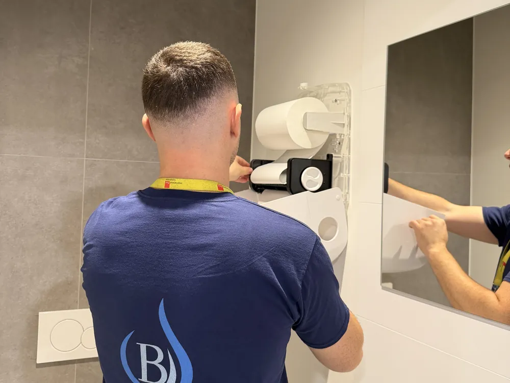 Un agent Bora Clean Group recharge le distributeur d'essuie-mains de sanitaires de bureau